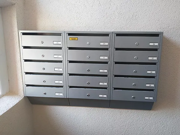 Piktograma sublokuotos sidabrinės pašto dėžutės laiptinėje